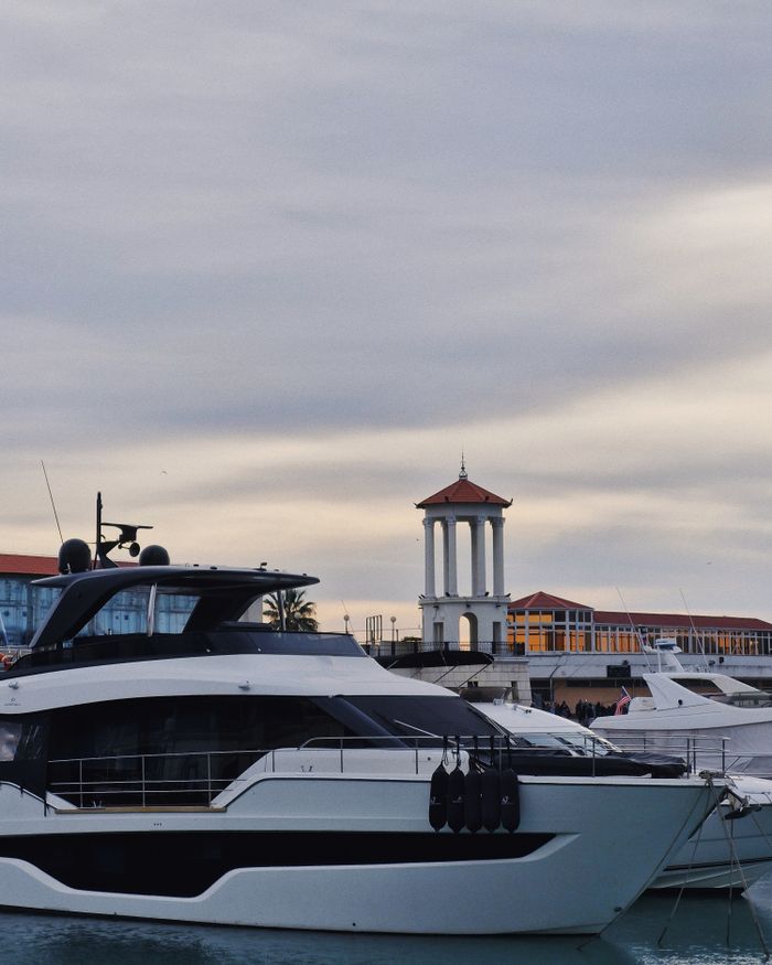 gallery-1 Elegant yacht stationed by a bustling marina with picturesque views and landmark tower.
